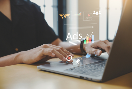 A person using a laptop with digital marketing and advertisement icons, including charts and social media, projected above the keyboard—highlighting the importance of staying alert to threats like SEO poisoning in online campaigns.